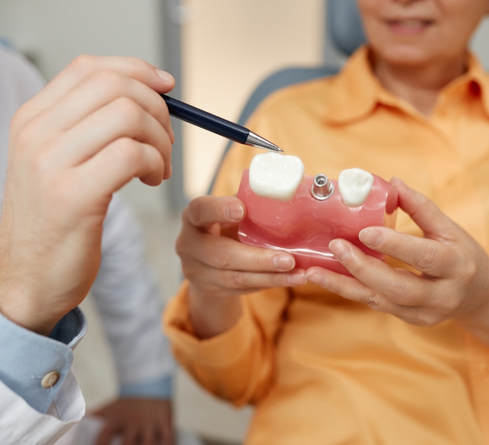 Dentist showing a model of a dental implant to a patient