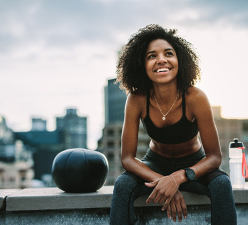 Staten Island dental implant patient smiling on roof of building after exercise