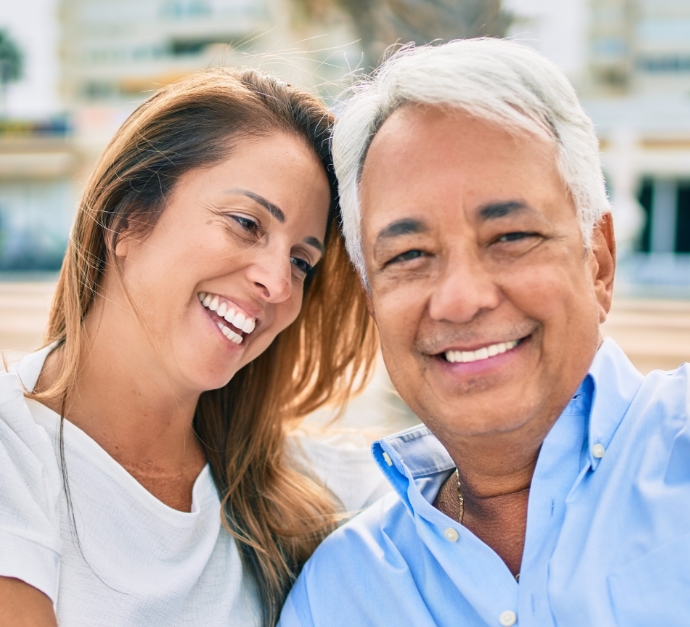 Senior man and woman smiling with implant dentures in Staten Island