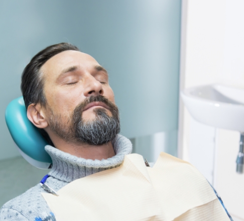Man relaxing in dental chair with eyes closed