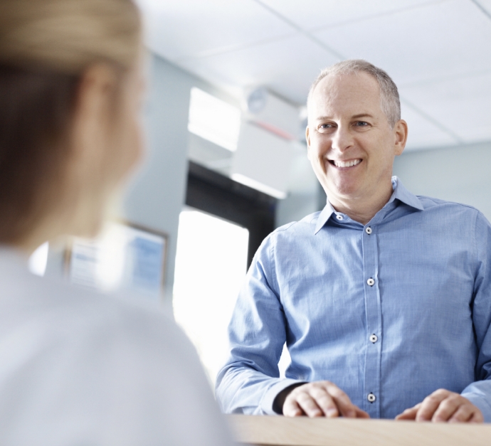 Man smiling at dental office receptionist