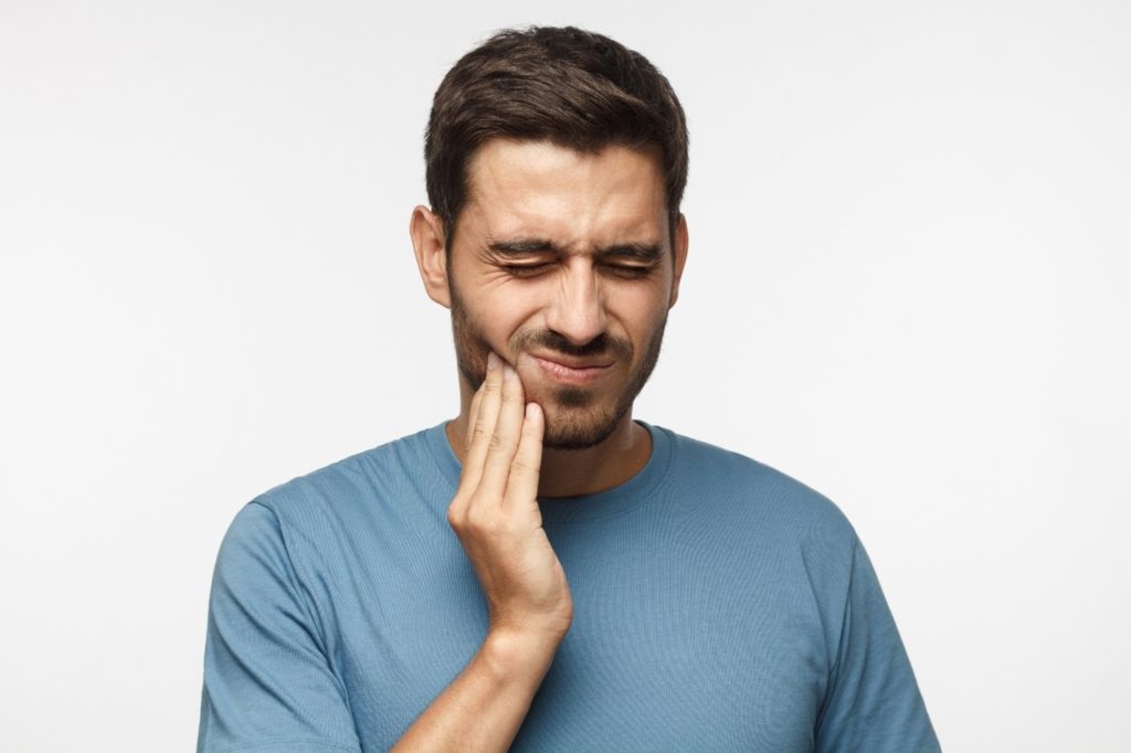 person with toothache holding their cheek